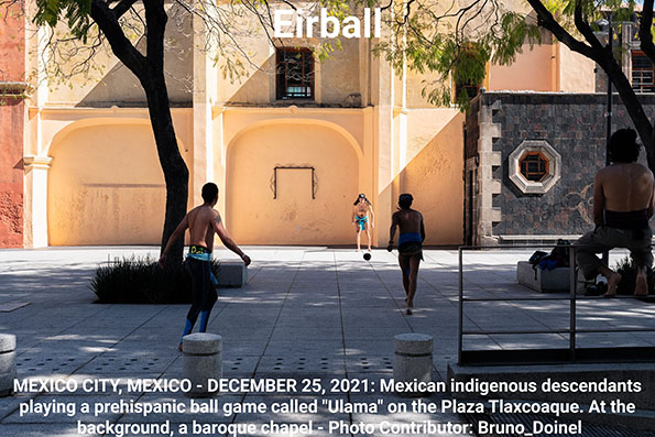 MEXICO CITY, MEXICO - DECEMBER 25, 2021: Mexican indigenous descendants playing a prehispanic ball game called "Ulama" on the Plaza Tlaxcoaque. At the background, a baroque chapel.